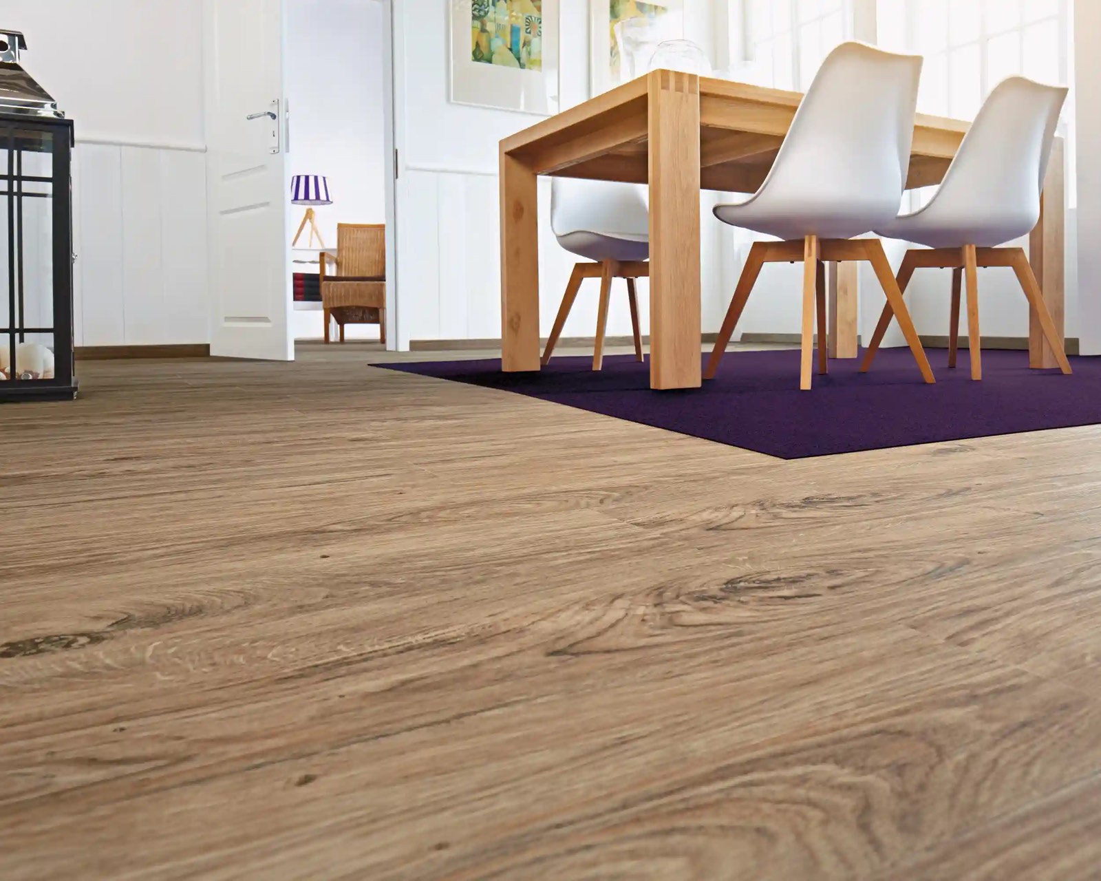 Esszimmer mit Holzboden in Eichenoptik, Holztisch und weißen Stühlen