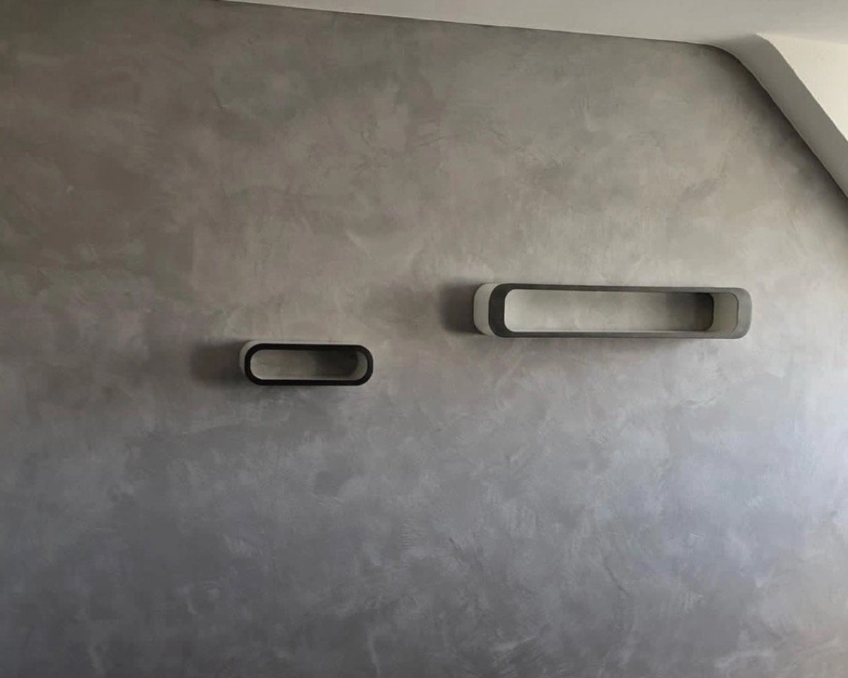 Grau gewischter Kalkputz an einer Wohnzimmerwand mit zwei Wandregalen